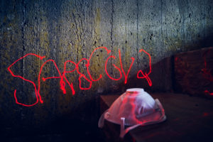 Symbolic picture, menekel on concrete wall, lettering Sars Cov 2, handwriting with red laser beam, respirator Symbolic picture, menekel on concrete wall, lettering Sars Cov 2, handwriting with red laser beam, respirator